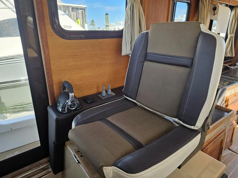 Slide: The Image of Interior of a 2014 Ranger Tugs 31-CB featuring a cushioned seat and control console. - 33
