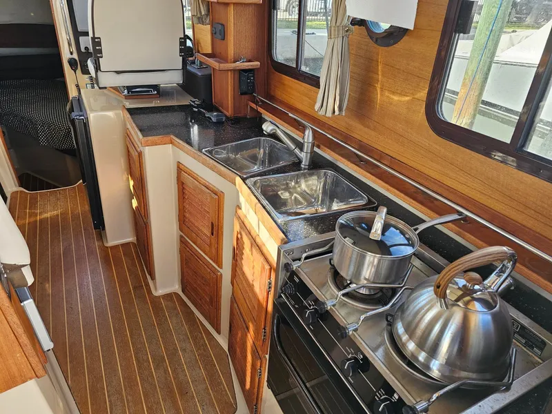 Slide: The Image of The galley of a 2014 Ranger Tugs 31-CB with wood paneling, sink, and stove. - 26