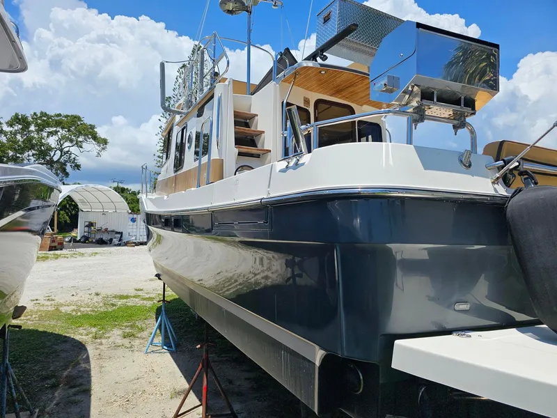 Slide: The Image of A 2014 Ranger Tugs 31-CB is on a boatyard. It features a glossy, dark blue hull. - 4
