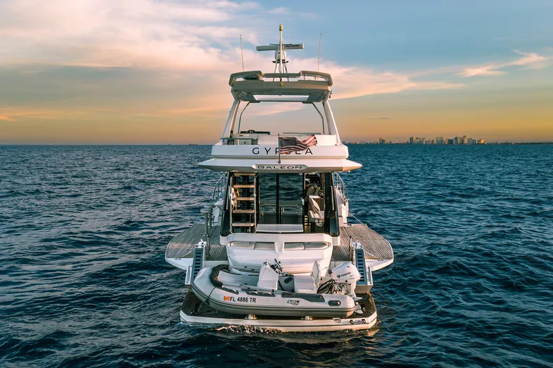 Slide: The Image of 2021 Galeon 500 Fly yacht on open sea at sunset, city skyline in background. - 38