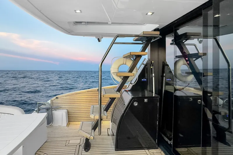 Slide: The Image of Luxury Galeon 500 Fly yacht deck with modern staircase, ocean view, and sunset sky, 2021 model. - 17