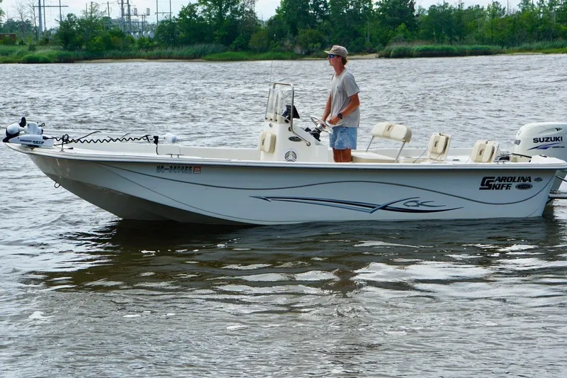 Slide: The Image of 2017 Carolina Skiff 218 DLV boat on water with person steering. - 3