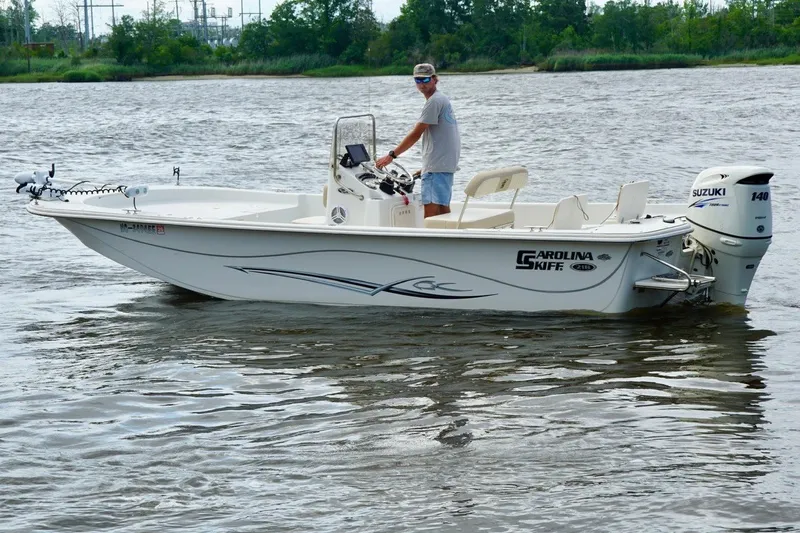 Slide: The Image of 2017 Carolina Skiff 218 DLV boat on water with Suzuki outboard motor. - 4