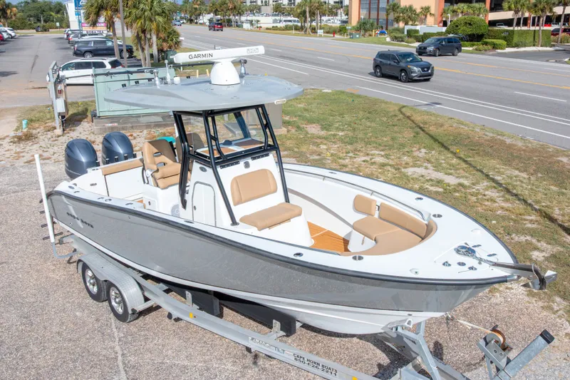 Slide: The Image of 2018 Cape Horn 27XS boat on trailer, parked near a road, featuring dual engines. - 2