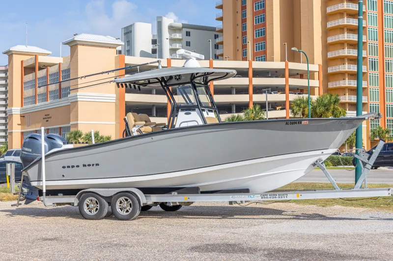 The Image of 2018 Cape Horn 27XS boat on trailer, parked near modern buildings. - 0