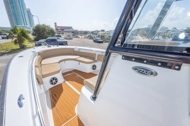Slide: The Image of 2018 Cape Horn 27XS boat with tan seating and wood-style flooring, docked near buildings. - 31