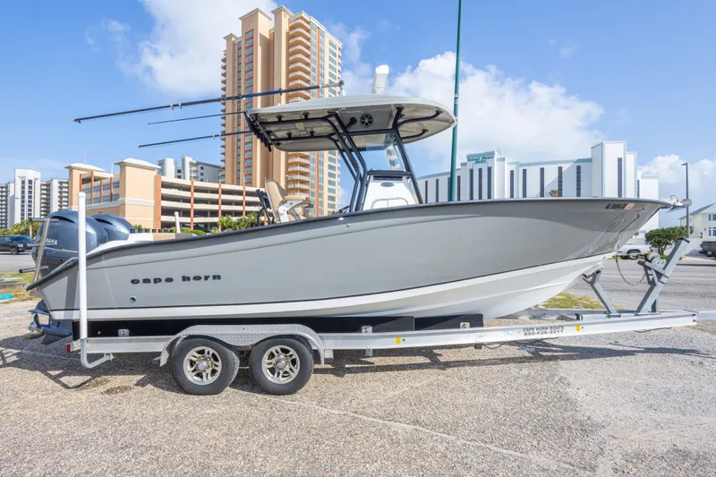 Slide: The Image of 2018 Cape Horn 27XS boat on trailer, parked near modern buildings under a clear sky. - 12