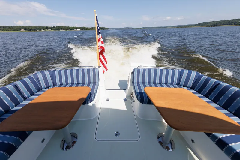 Slide: The Image of Back Cove 41 boat's rear view with striped seating and wooden tables, cruising on open water. - 42