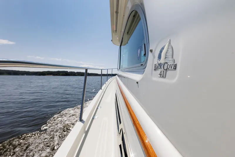 Slide: The Image of 2020 Back Cove 41 yacht cruising on a serene lake under a clear sky. - 44