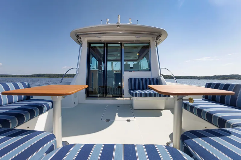 Slide: The Image of 2020 Back Cove 41 yacht with striped seating and wooden tables on deck. - 6