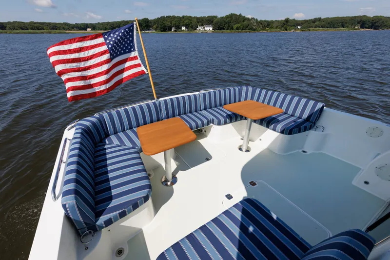 Slide: The Image of Back Cove 41 (2020) boat deck with striped seating and American flag on a calm lake. - 40