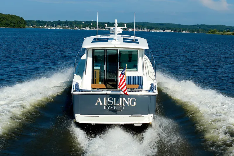Slide: The Image of Back Cove 41 yacht cruising on a river, displaying American flag, 2020 model. - 56