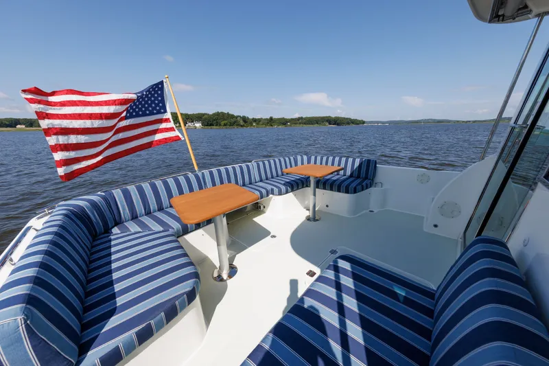 Slide: The Image of Back Cove 41 (2020) boat with striped seating, American flag, on a serene lake. - 41