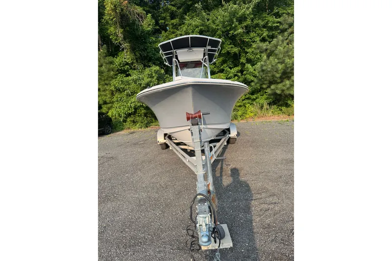 Slide: The Image of 2020 Sea Hunt Ultra 211 boat on trailer, parked on asphalt with lush greenery background. - 2
