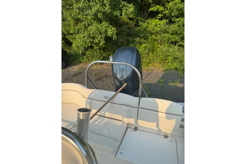 Slide: The Image of 2020 Sea Hunt Ultra 211 boat with outboard motor, parked near lush greenery. - 17
