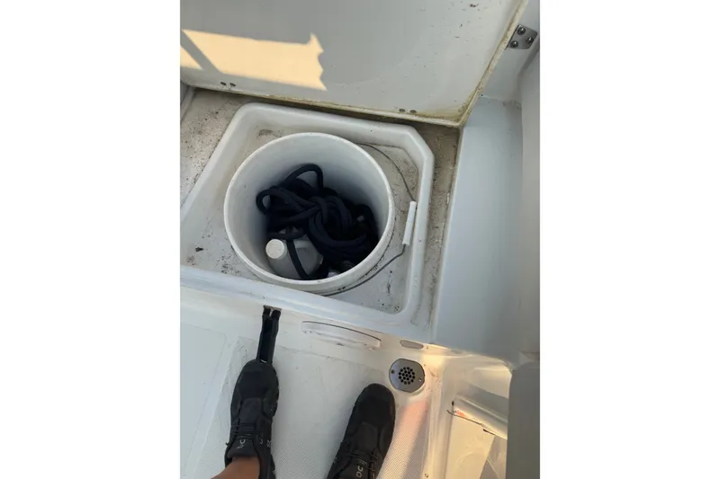 Slide: The Image of 2020 Sea Hunt Ultra 211 boat storage compartment with rope and footwear visible. - 14