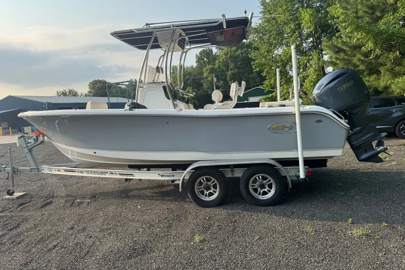 The Image of 2020 Sea Hunt Ultra 211 boat on trailer, parked outdoors with Yamaha outboard motor. - 0