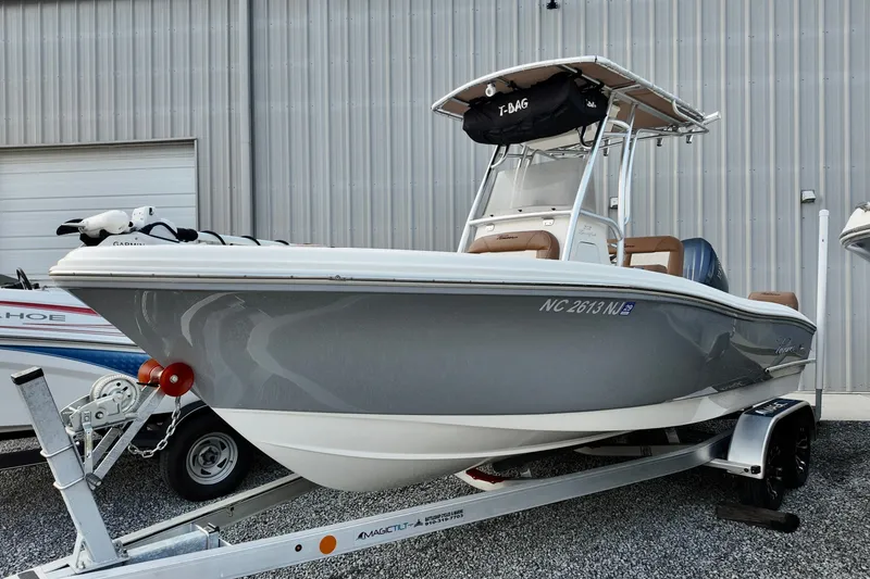 The Image of 2025 Pioneer 202 Sportfish boat on trailer, gray hull, parked outside a metal building. - 1