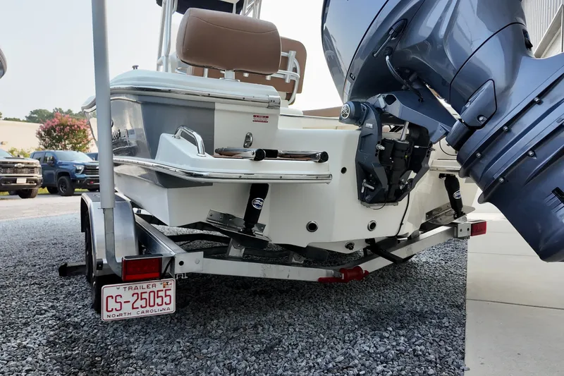 Slide: The Image of 2025 Pioneer 202 Sportfish boat on trailer, featuring powerful outboard motor, parked on gravel. - 12