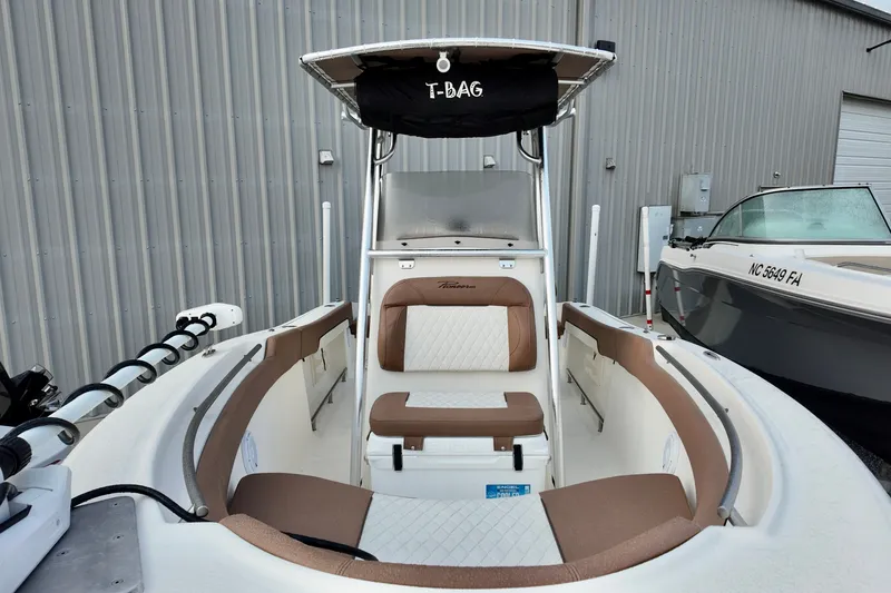 Slide: The Image of 2025 Pioneer 202 Sportfish boat interior with seating and T-top, docked beside another vessel. - 19