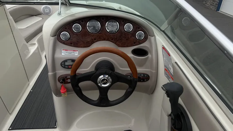 Slide: The Image of The image shows the cockpit of a 2004 Sea Ray 200 Sundeck boat with a wood steering wheel and instruments. - 28