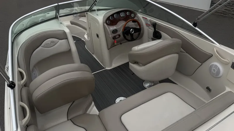 Slide: The Image of Interior of a 2004 Sea Ray 200 Sundeck boat with beige seating and a sleek dashboard. - 26
