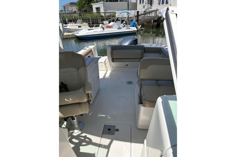 Slide: The Image of 2018 Sailfish 245 DC boat interior with seating and docked boats in background. - 25