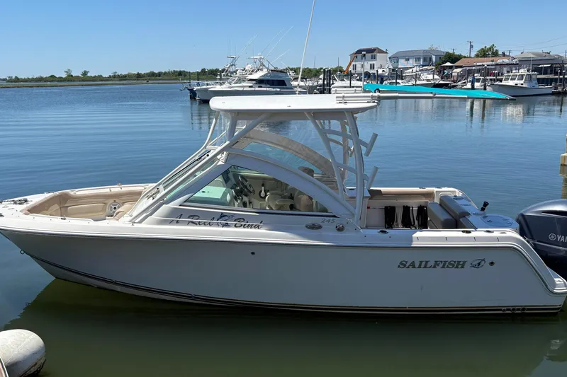 Slide: The Image of 2018 Sailfish 245 DC boat docked in a serene marina setting. - 3