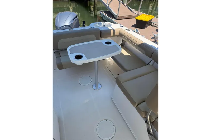 Slide: The Image of 2018 Sailfish 245 DC boat interior with seating and table, docked by the water. - 26