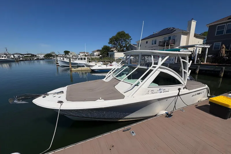 Slide: The Image of 2018 Sailfish 245 DC boat docked at a marina, under clear blue skies. - 10