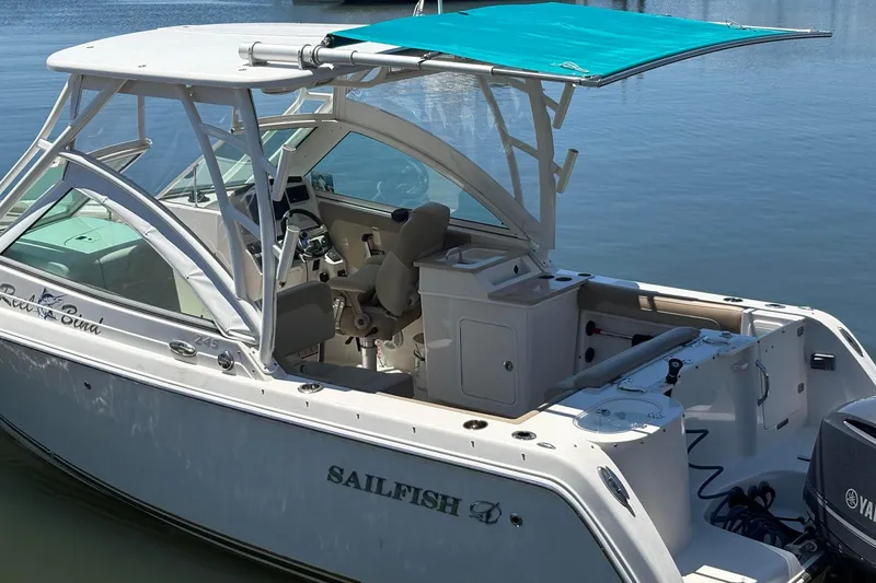 Slide: The Image of 2018 Sailfish 245 DC boat with canopy, docked on calm water. - 2