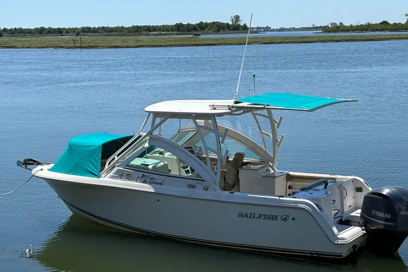 Slide: The Image of 2018 Sailfish 245 DC boat with teal canopy on calm water. - 7