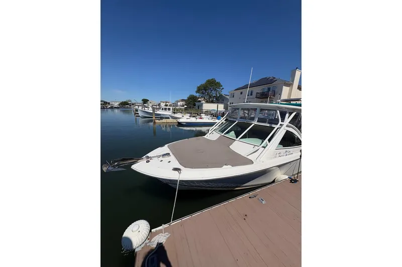 Slide: The Image of 2018 Sailfish 245 DC boat docked in a serene marina setting. - 9