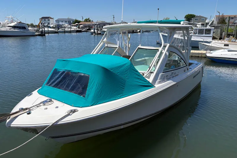 Slide: The Image of 2018 Sailfish 245 DC boat docked in marina with teal canopy cover. - 4