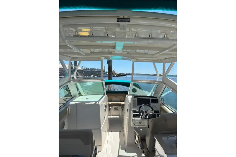 Slide: The Image of 2018 Sailfish 245 DC boat interior with helm, steering wheel, and waterfront view. - 23