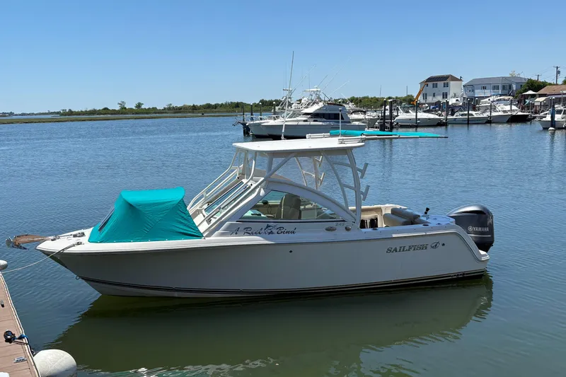 Slide: The Image of 2018 Sailfish 245 DC boat docked in a marina with clear blue skies. - 5