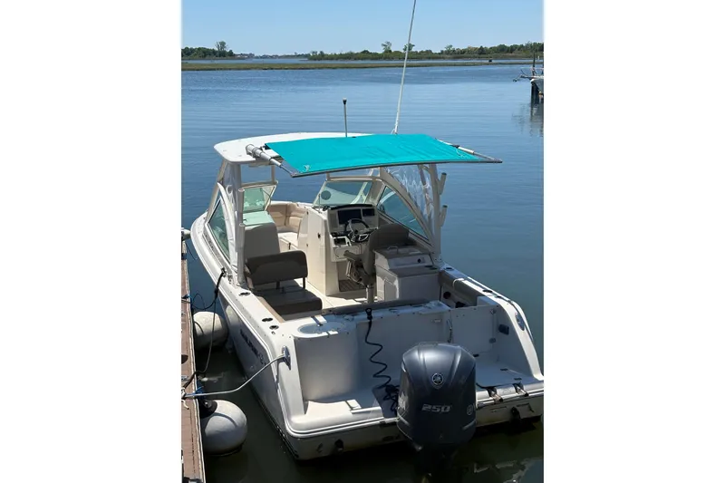 Slide: The Image of 2018 Sailfish 245 DC boat docked with turquoise canopy and outboard motor. - 22