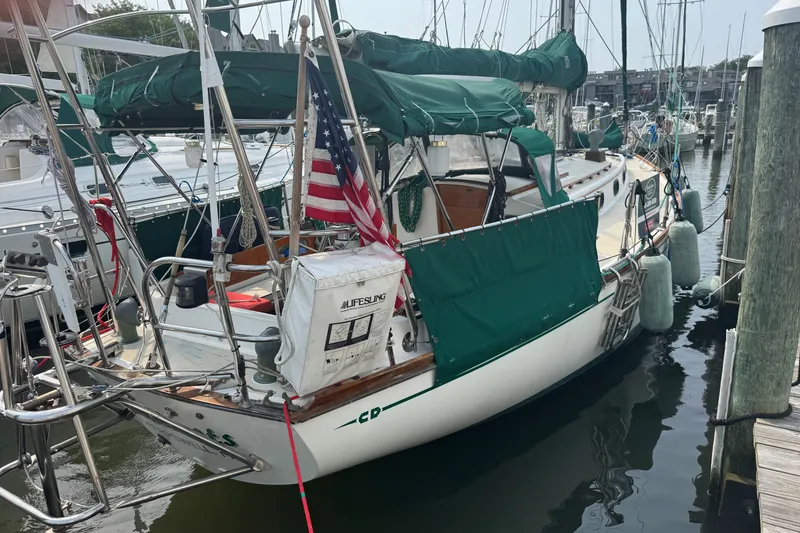 Slide: The Image of 1986 Cape Dory 36 sailboat docked, featuring green covers and an American flag. - 18