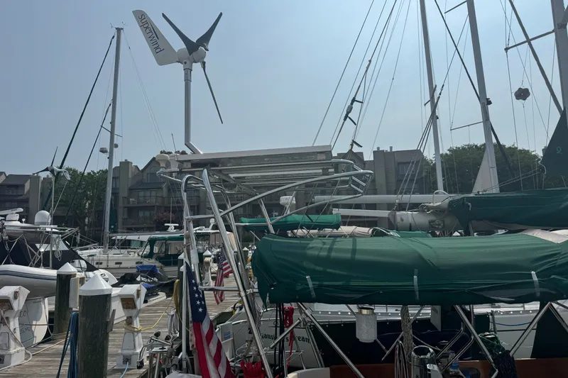 Slide: The Image of 1986 Cape Dory 36 sailboat docked at marina with wind turbines and green covers. - 19