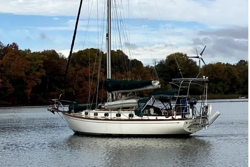 The Image of A 1986 Cape Dory 36 sailboat rests calmly on a lake, surrounded by autumn trees. - 0