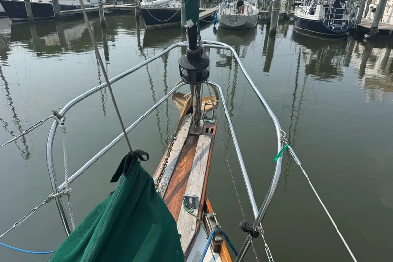 Slide: The Image of 1986 Cape Dory 36 sailboat bow at marina, surrounded by calm water and docked boats. - 24