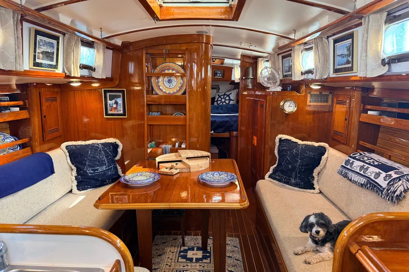 Slide: The Image of Cozy interior of 1986 Cape Dory 36 sailboat with wooden furnishings and a small dog. - 1