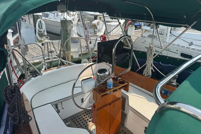 Slide: The Image of 1986 Cape Dory 36 sailboat cockpit with green canopy and steering wheel at marina. - 2