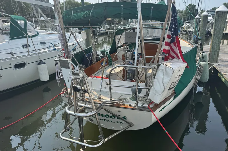 Slide: The Image of 1986 Cape Dory 36 sailboat docked, featuring green canvas covers and an American flag. - 17