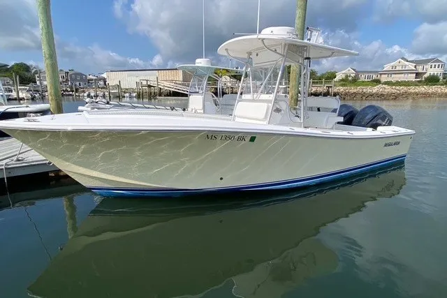 Slide: The Image of 2006 Regulator 23 Forward Seating boat docked in a marina, reflecting on calm water. - 8