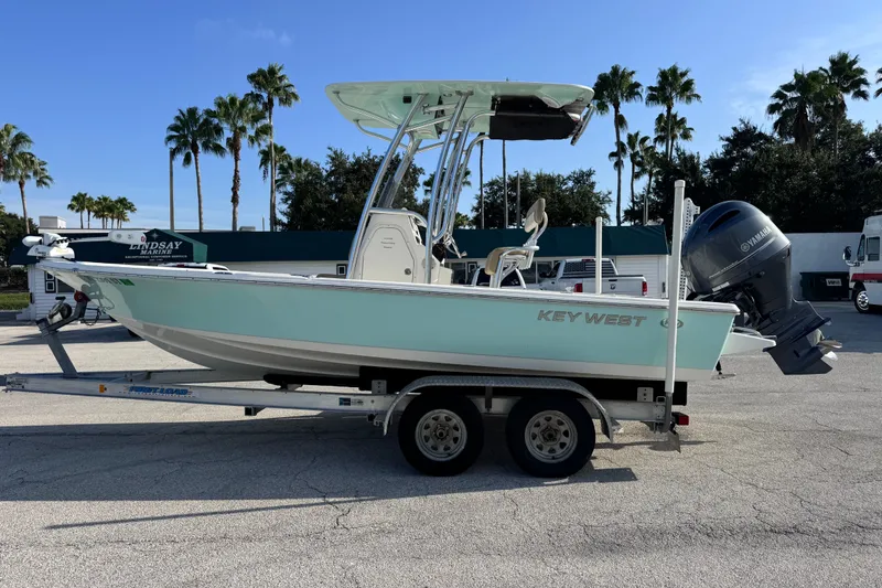 Slide: The Image of 2020 Key West 210 Bay Reef boat on trailer, parked outdoors with palm trees in background. - 14