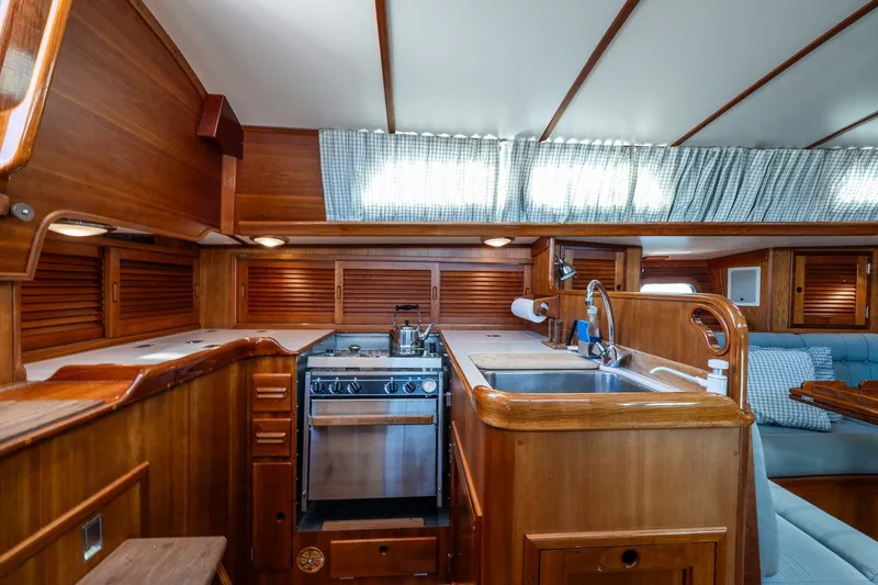 Slide: The Image of Interior of 1995 Hinckley Sou'wester 42 MKII yacht, featuring a wooden galley with stove and sink. - 13