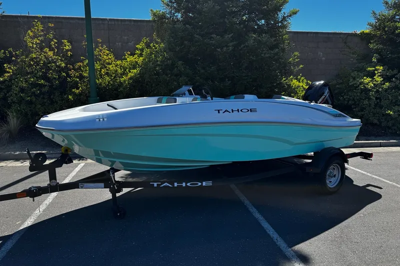 The Image of 2026 Tahoe T16 boat on trailer in parking lot, surrounded by greenery. - 0