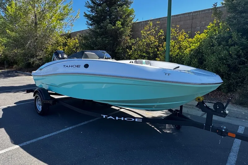 Slide: The Image of 2026 Tahoe T16 boat on trailer in parking lot, surrounded by trees. - 2