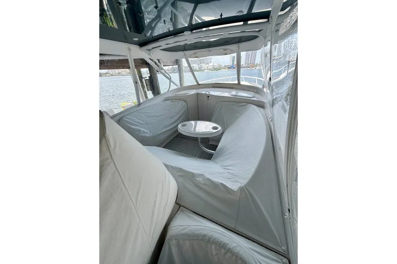 Slide: The Image of 2020 Intrepid 407 Cuddy boat interior with seating and table, docked by the water. - 16